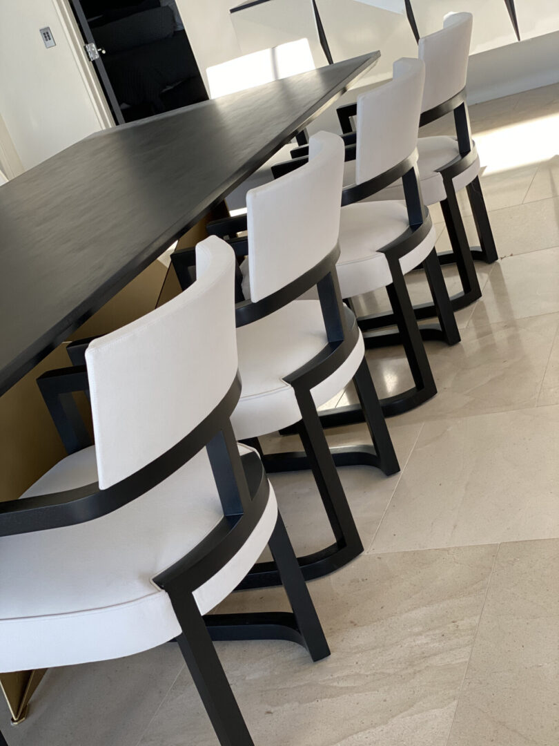 Row of white upholstered chairs by black table