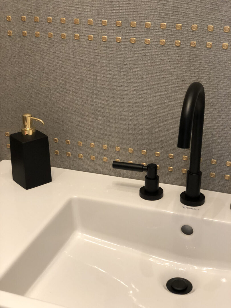 White sink with black faucet and gold studs
