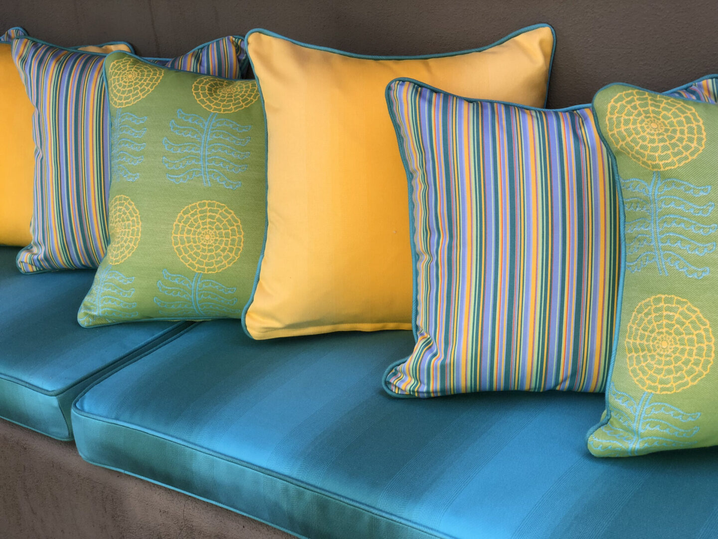 Colorful striped and floral throw pillows on teal