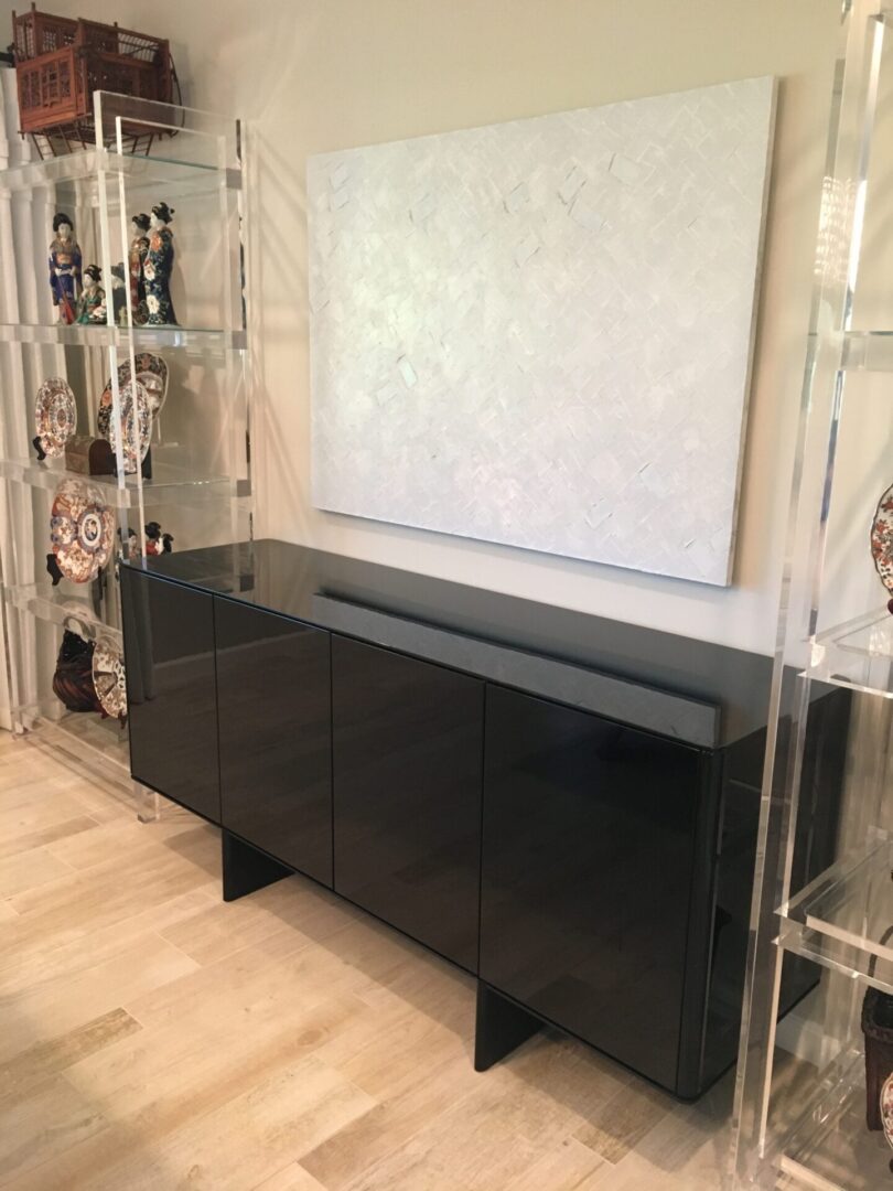 Black glossy sideboard under white abstract painting
