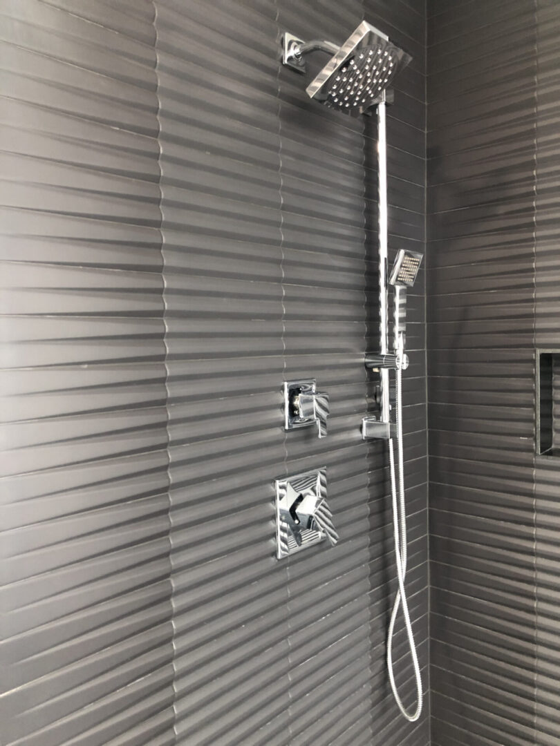 Chrome shower fixtures on ribbed dark tiles